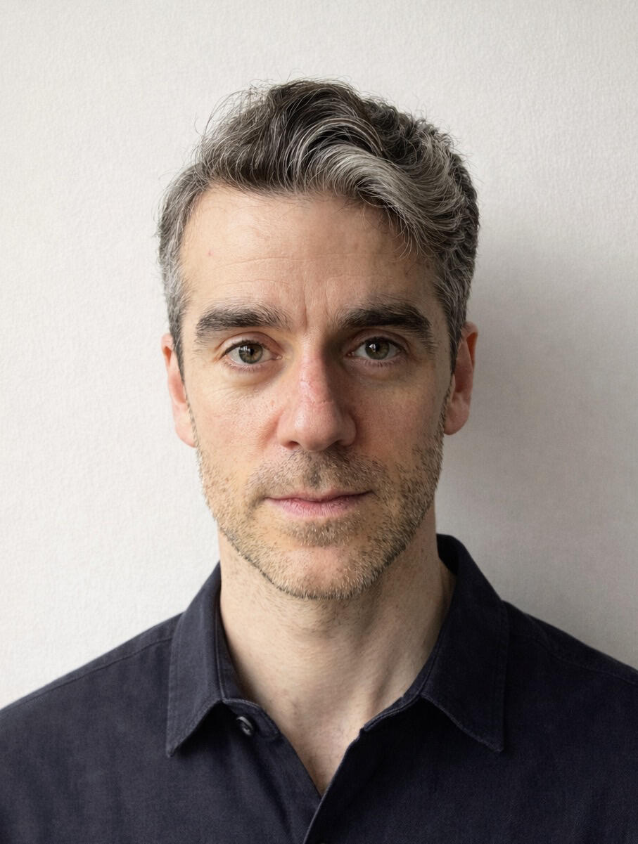 Photograph of me in a black T shirt against a white wall